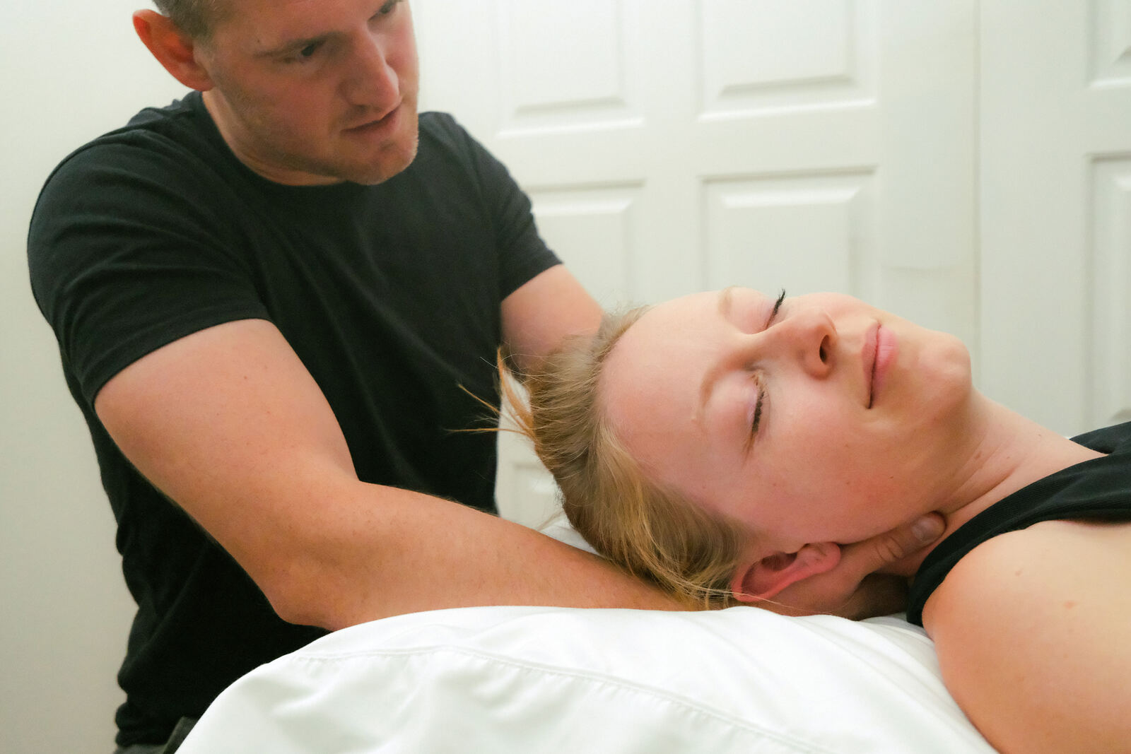 Dr. Kyle Pratt performing hands on cervical treatment with a patient relaxed on the table