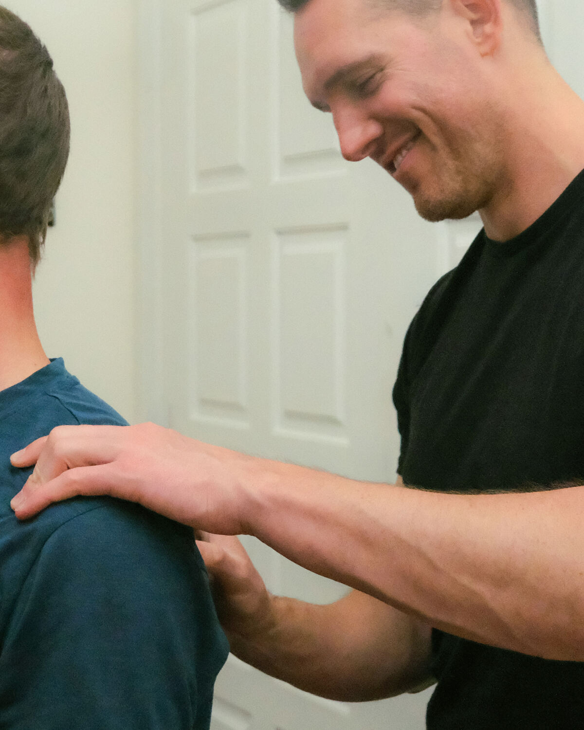 Dr. Kyle Pratt smiling while working through a patient's shoulder in the clinic
